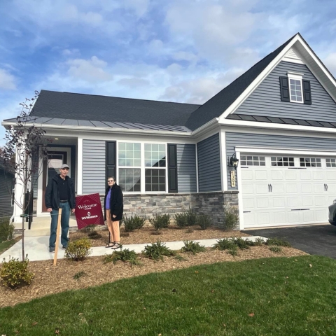 Family celebrating new home purchase on front porch of two-story brick NVHomes property