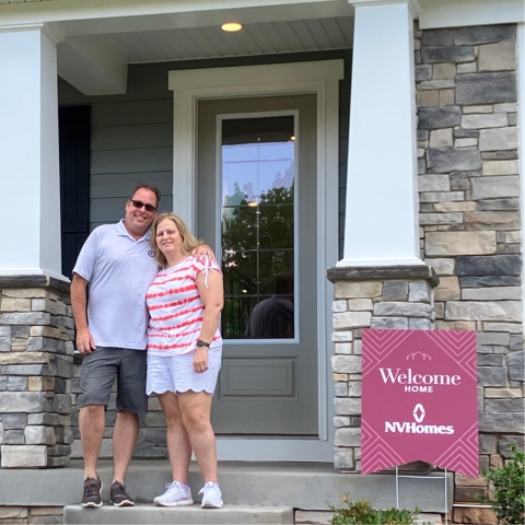 Happy couple standing on front steps of newly purchased NVHomes property