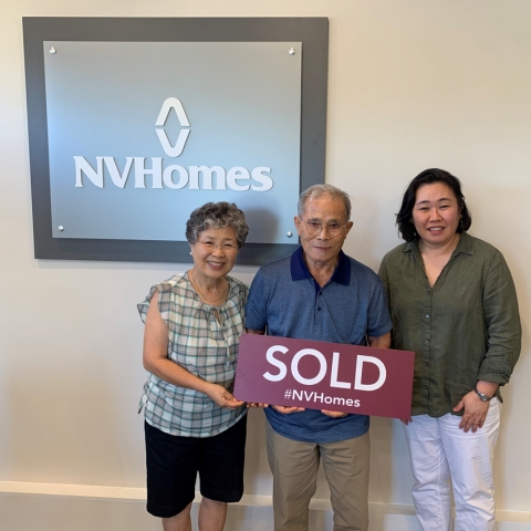 Group celebrating new home purchase with 'SOLD #NVHomes' sign